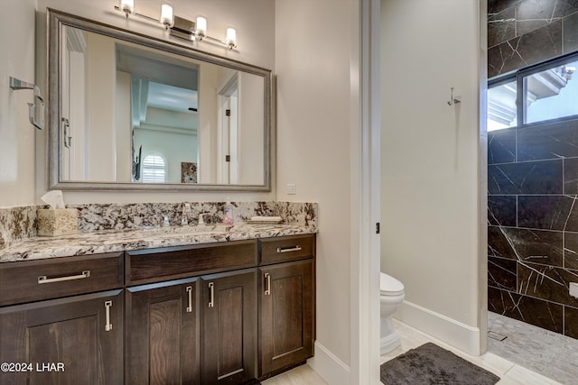 full bath featuring baseboards, a tile shower, vanity, and toilet