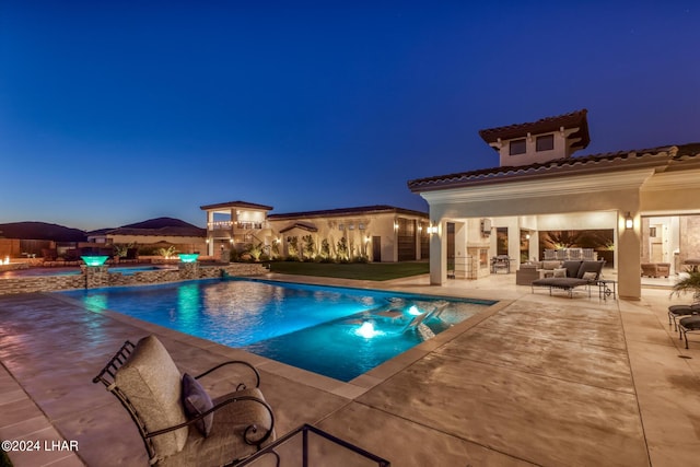 pool at night featuring a fenced in pool, a patio area, and an outdoor living space