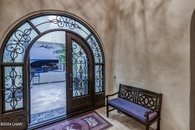 tiled foyer entrance featuring a ceiling fan, arched walkways, and a towering ceiling