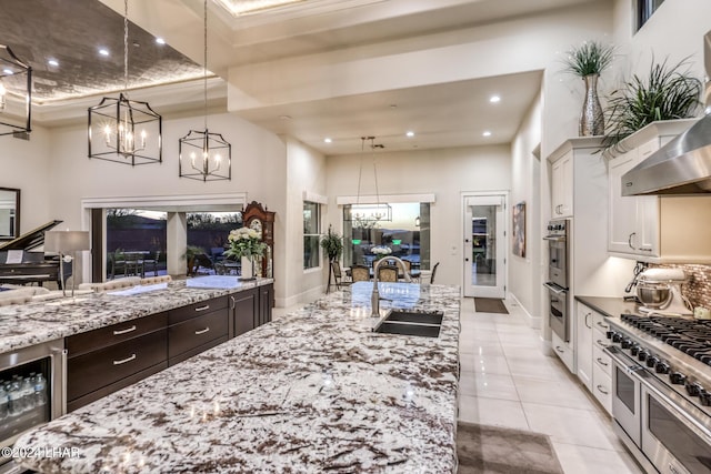 kitchen with dark brown cabinetry, beverage cooler, stainless steel appliances, a sink, and white cabinetry