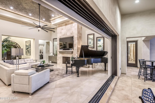 living area featuring ceiling fan, a fireplace, a high ceiling, and recessed lighting