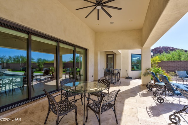 view of patio featuring outdoor dining area, fence, and a ceiling fan