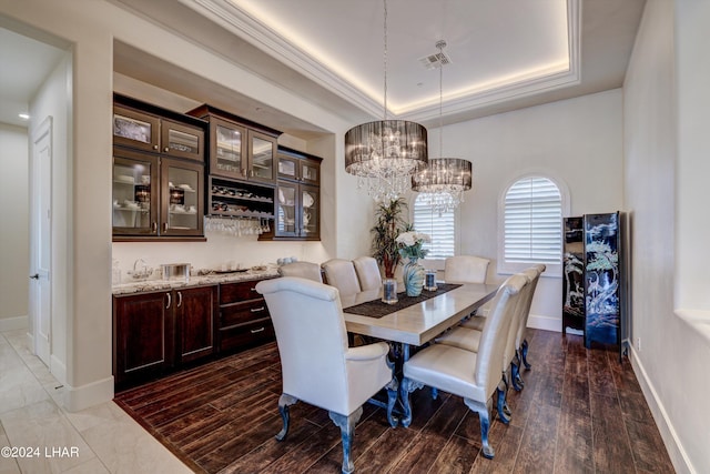 dining room featuring baseboards, visible vents, a raised ceiling, ornamental molding, and wood finished floors