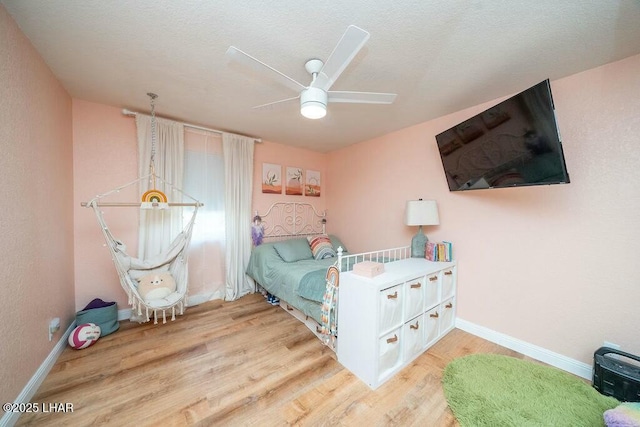 bedroom featuring ceiling fan, baseboards, a textured ceiling, and wood finished floors