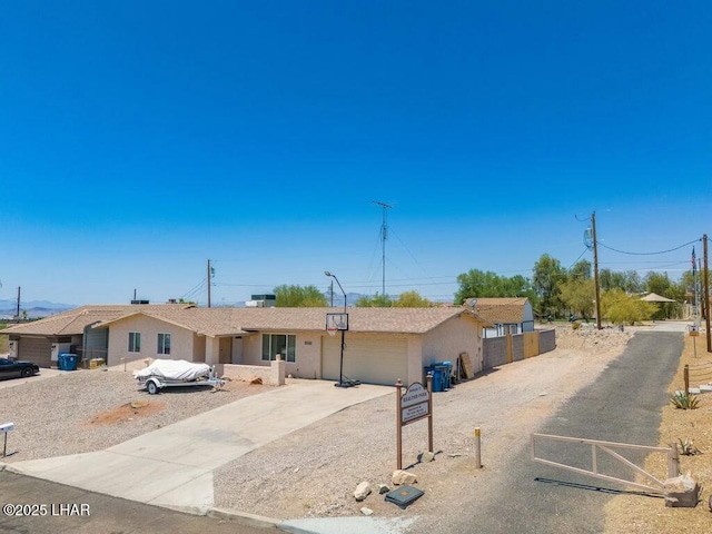 ranch-style house featuring concrete driveway, an attached garage, fence, and stucco siding