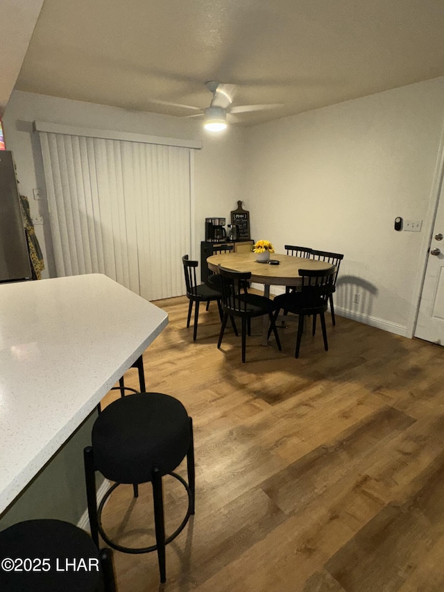 dining area featuring baseboards, light wood-type flooring, and a ceiling fan