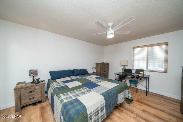 bedroom with a ceiling fan, wood finished floors, baseboards, and a textured ceiling