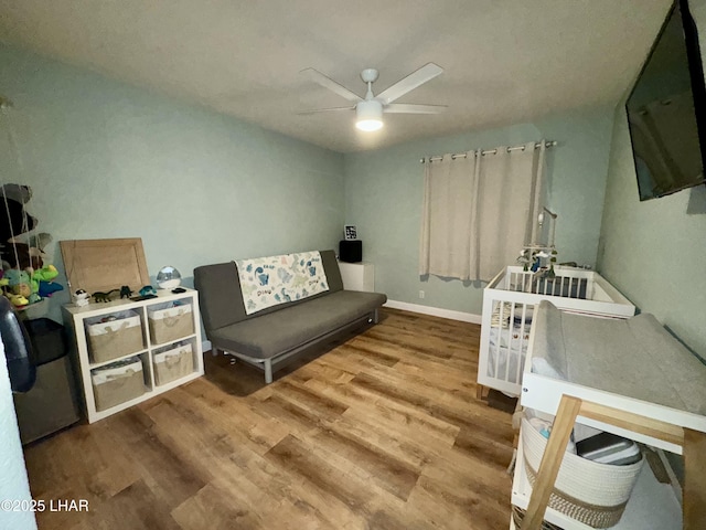 sitting room with baseboards, ceiling fan, and wood finished floors