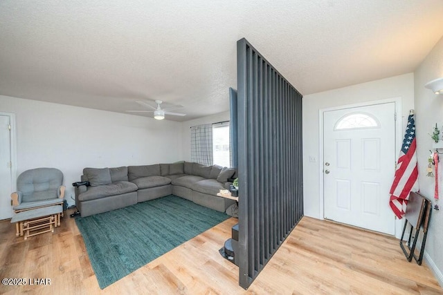 living area with a ceiling fan, wood finished floors, and a textured ceiling