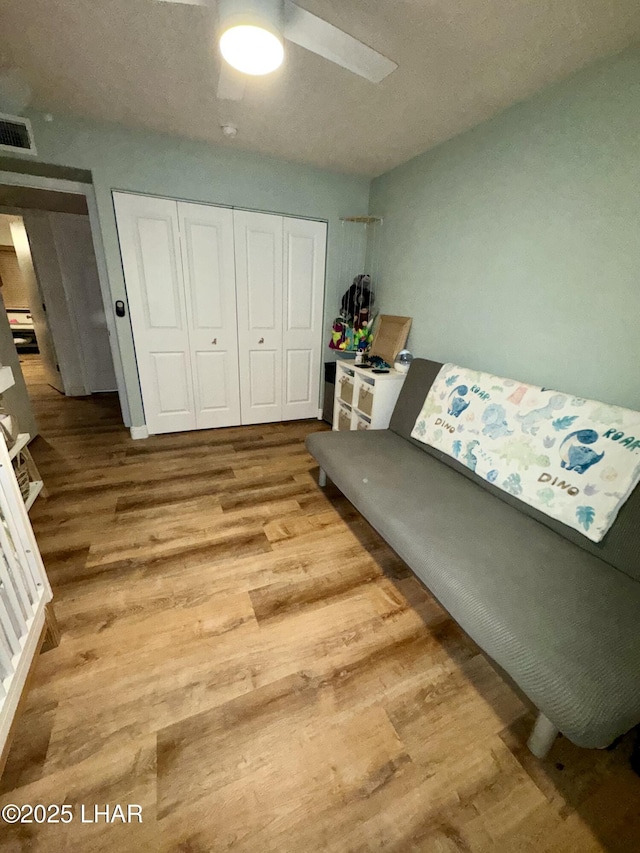 living area featuring wood finished floors, visible vents, and ceiling fan