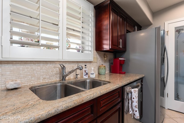 kitchen featuring a sink, dark brown cabinets, appliances with stainless steel finishes, backsplash, and light stone countertops