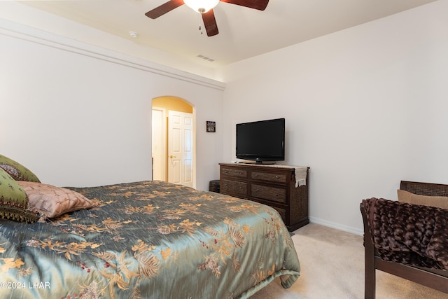 bedroom featuring light carpet, baseboards, visible vents, arched walkways, and ceiling fan