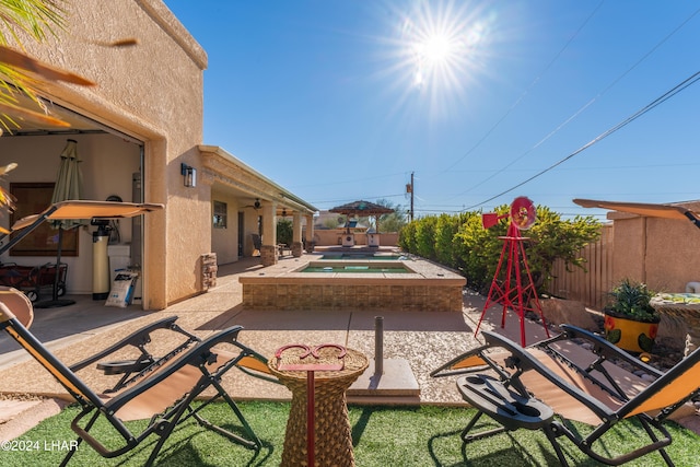 view of patio / terrace featuring ceiling fan, an in ground hot tub, and a fenced backyard