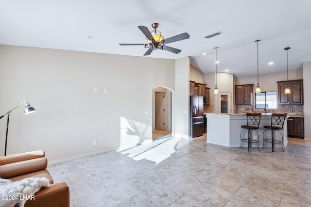 kitchen with tasteful backsplash, stainless steel fridge with ice dispenser, a kitchen breakfast bar, a kitchen island, and light stone countertops