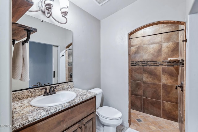 bathroom featuring a tile shower, vanity, and toilet