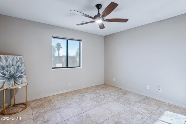 spare room with ceiling fan and light tile patterned flooring