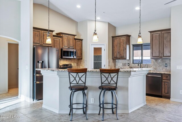 kitchen with light stone countertops, a breakfast bar area, stainless steel appliances, and a center island