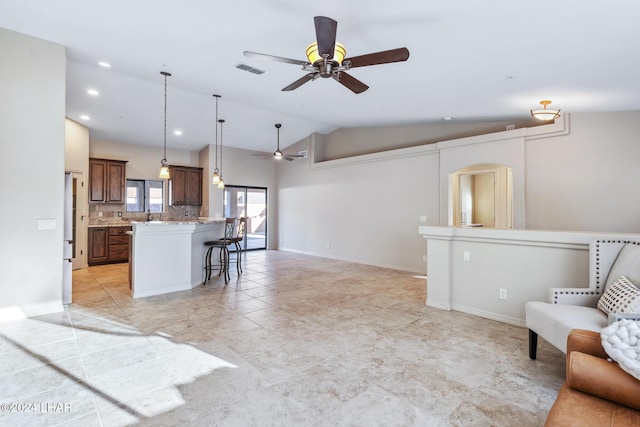 kitchen featuring lofted ceiling, a breakfast bar area, light stone counters, a kitchen island, and decorative backsplash