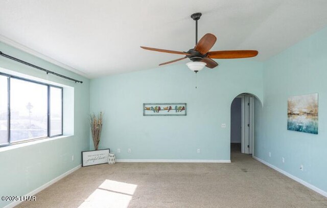 spare room featuring ceiling fan, light colored carpet, and vaulted ceiling