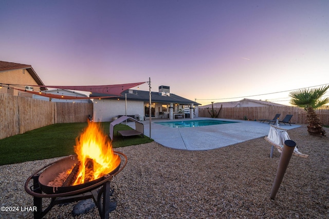 pool at dusk with a patio and a fire pit