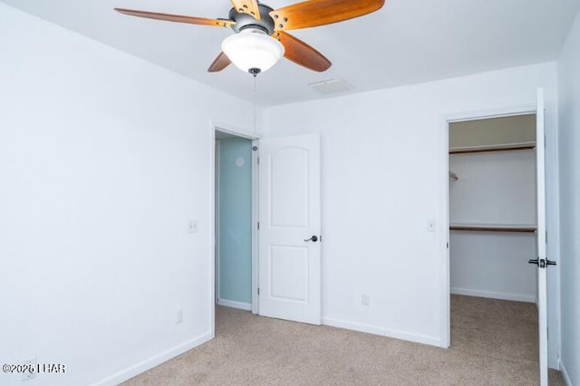 unfurnished bedroom featuring a spacious closet, light carpet, ceiling fan, and a closet