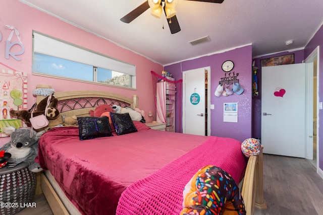 bedroom with hardwood / wood-style flooring, a textured ceiling, and ceiling fan