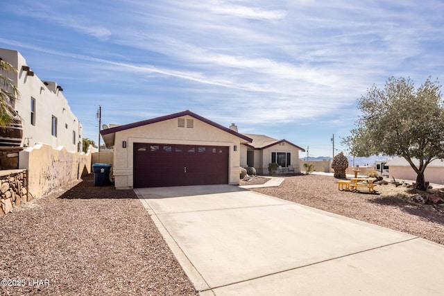 ranch-style house with a garage, fence, concrete driveway, and stucco siding