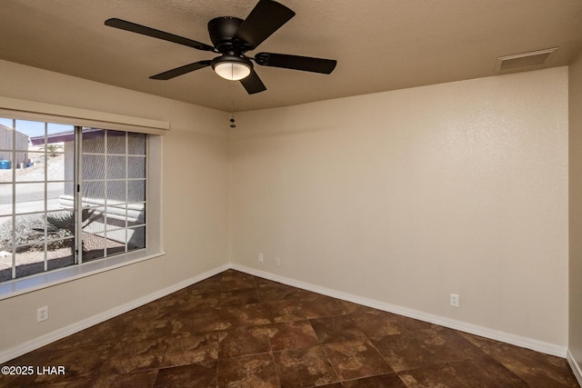 spare room with stone finish floor, visible vents, and baseboards