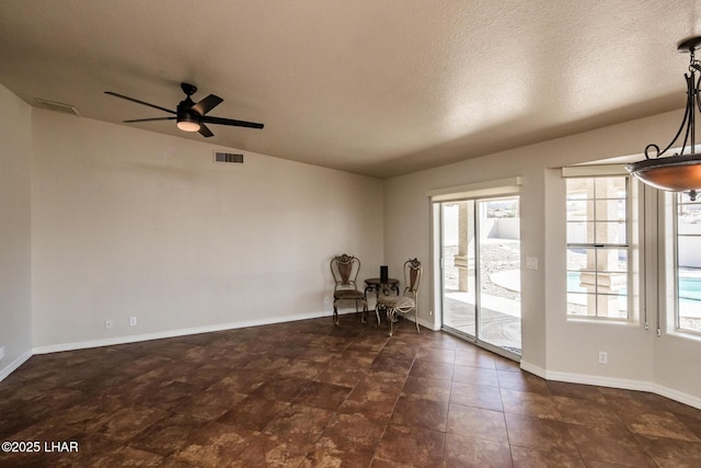 unfurnished room with visible vents, ceiling fan, a textured ceiling, and baseboards