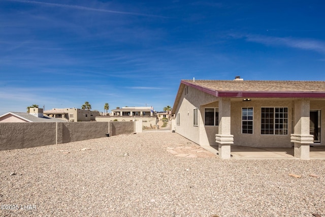 exterior space with roof with shingles, a fenced backyard, a patio, and stucco siding