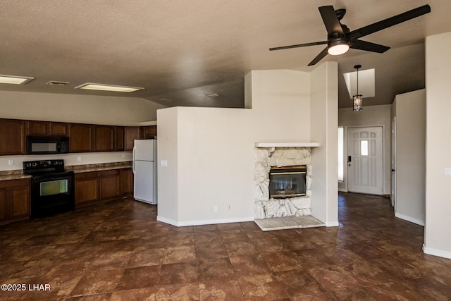 kitchen featuring a fireplace, visible vents, vaulted ceiling, black appliances, and baseboards