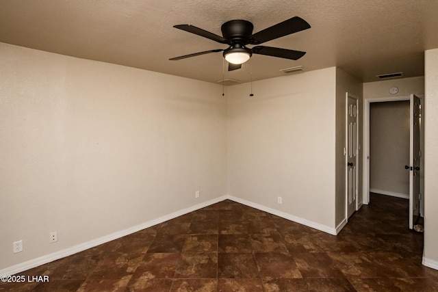 empty room with visible vents, a textured ceiling, and baseboards