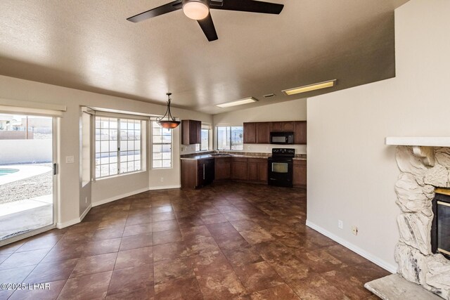 kitchen with lofted ceiling, decorative light fixtures, black appliances, a fireplace, and a sink