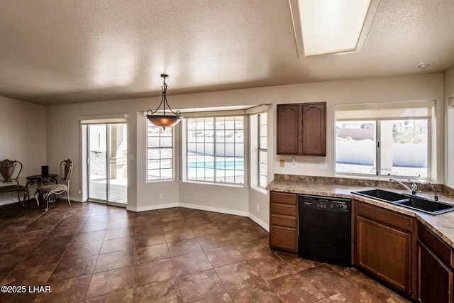 kitchen featuring decorative light fixtures, a sink, a textured ceiling, dishwasher, and baseboards