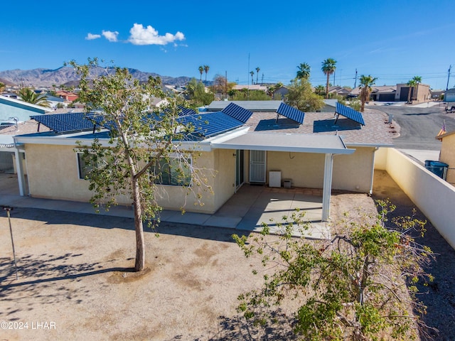 back of property with a mountain view and a patio area