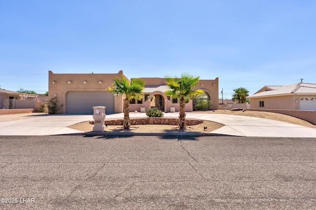 pueblo-style home featuring concrete driveway, an attached garage, a tile roof, and stucco siding