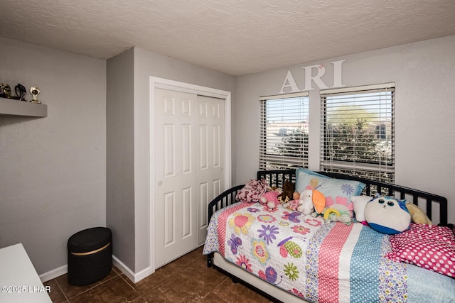 bedroom featuring a textured ceiling, a closet, and dark tile patterned floors