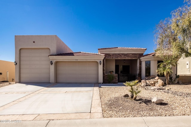 view of front of home with an attached garage, a tile roof, concrete driveway, and stucco siding