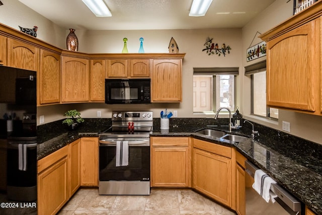 kitchen featuring appliances with stainless steel finishes, sink, and dark stone counters