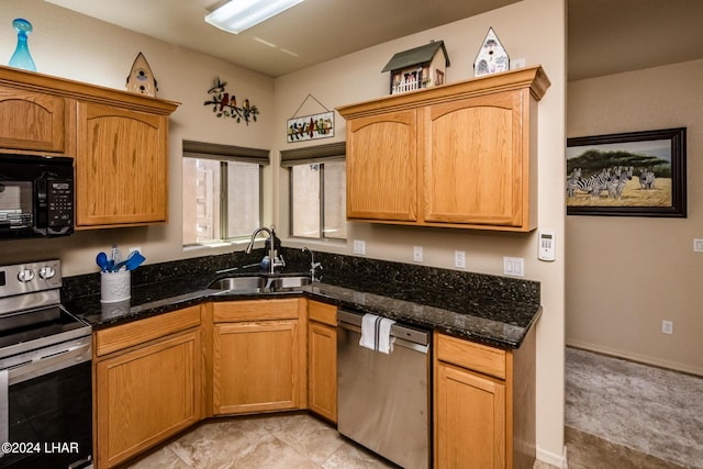 kitchen featuring sink, stainless steel appliances, and dark stone counters