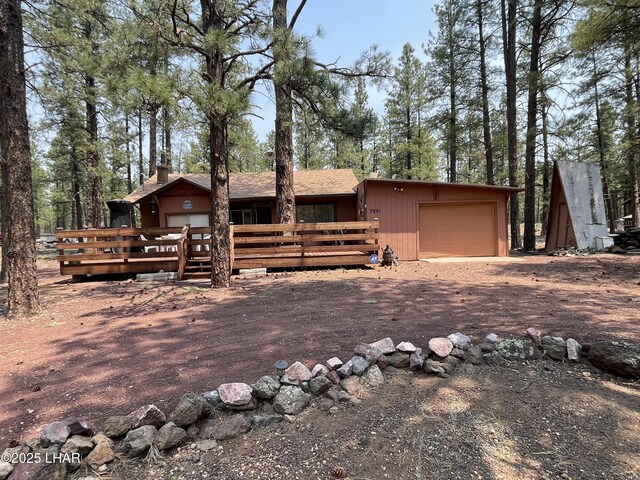 7681 E Robin Hood Rd, Williams, AZ 86046 - rustic home with a wooden deck, a chimney, an attached garage, and driveway
