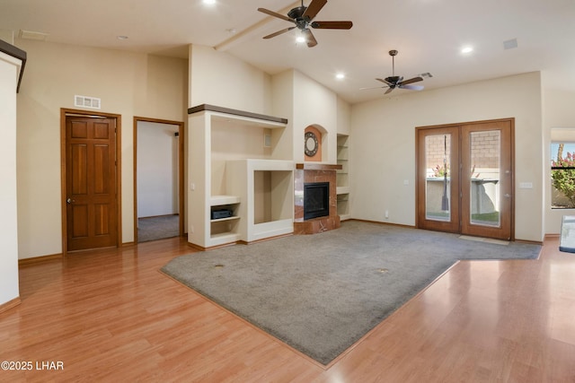2620 Via Palma, Lake Havasu City, AZ 86406 - unfurnished living room featuring ceiling fan, light wood-style flooring, a tile fireplace, built in shelves, and high vaulted ceiling