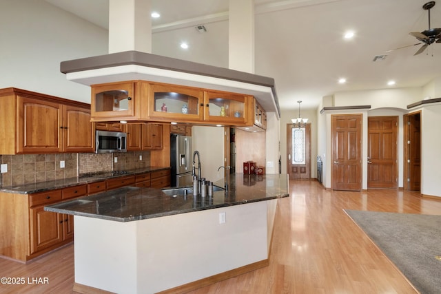 2620 Via Palma, Lake Havasu City, AZ 86406 - kitchen featuring appliances with stainless steel finishes, brown cabinets, glass insert cabinets, ceiling fan, and backsplash