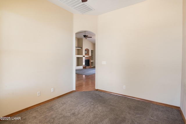 2620 Via Palma, Lake Havasu City, AZ 86406 - carpeted empty room with a ceiling fan, a fireplace with raised hearth, arched walkways, and built in features