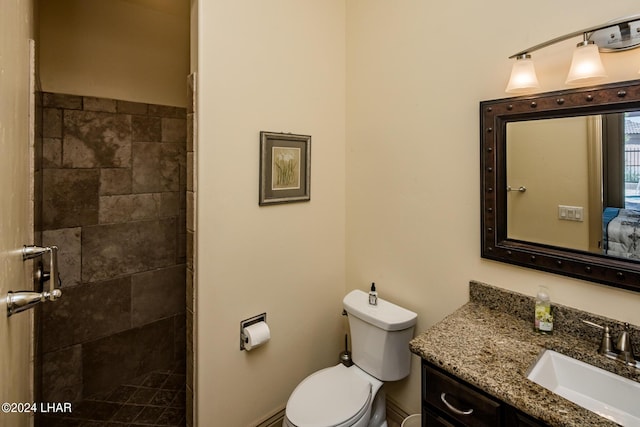 bathroom featuring vanity, toilet, and a tile shower