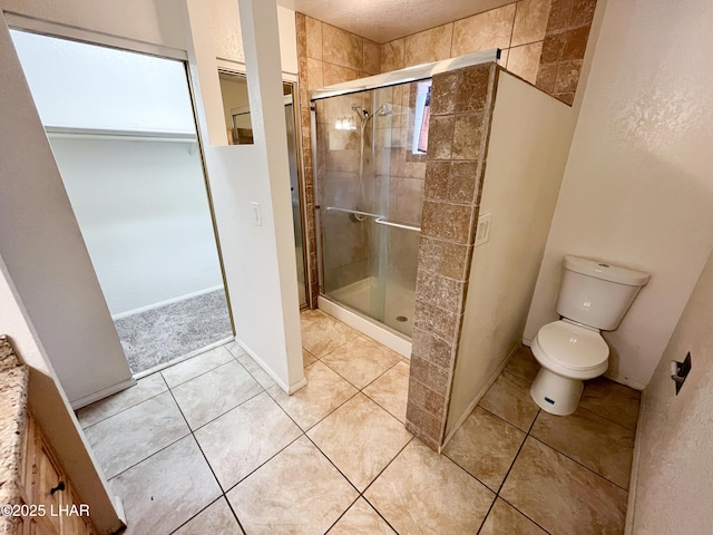 full bathroom with toilet, baseboards, tile patterned floors, a stall shower, and a walk in closet