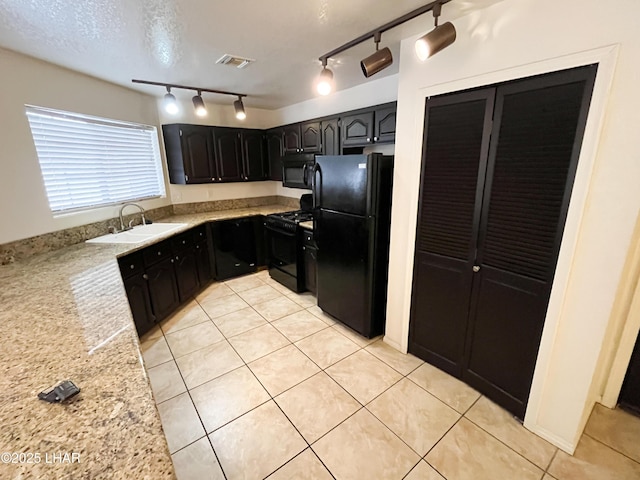 kitchen with light tile patterned floors, black appliances, light stone counters, and a sink