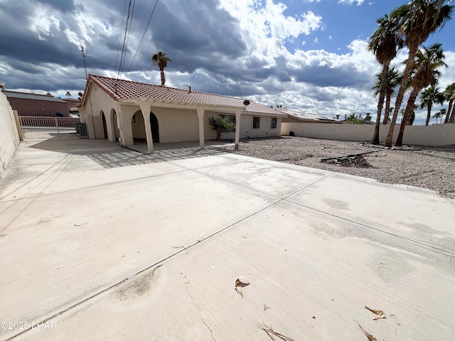 view of front of house with a patio area, fence, a tiled roof, and stucco siding