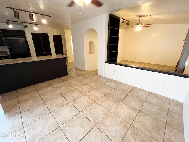 spare room with built in shelves, a ceiling fan, a textured ceiling, and tile patterned floors