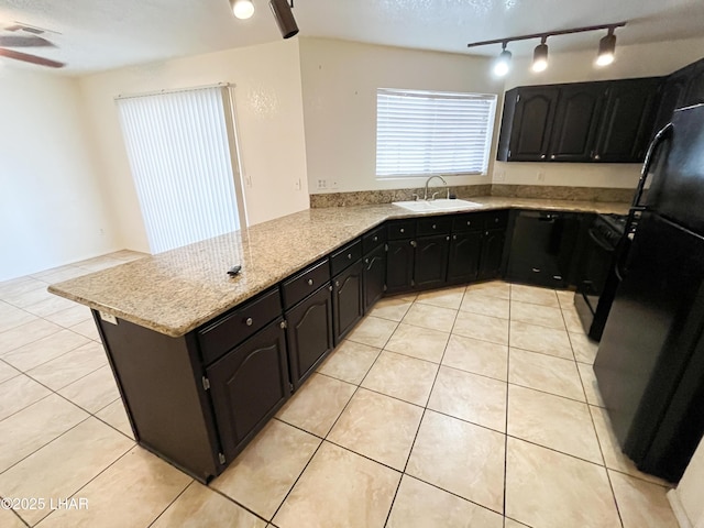 kitchen with light stone counters, light tile patterned flooring, a peninsula, a sink, and black appliances